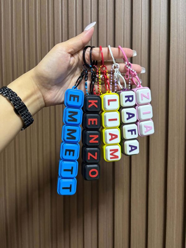 Hand holding five personalized name keychain clickers